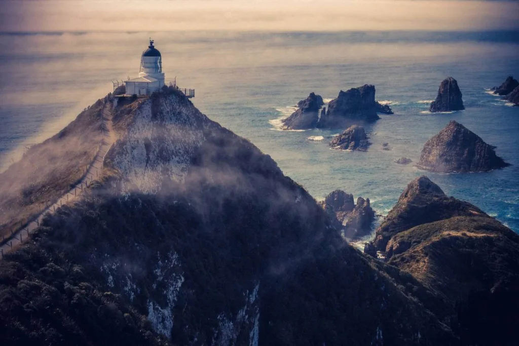 Photo of lighthouse with cliffs and the sea behind